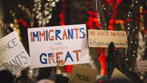 A protestor holding a sign reading "Immigrants Make America Great"