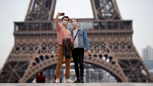 Two people in face masks take a selfie near the Eiffel Tower in France.