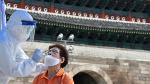 A health care worker takes test samples for the Covid-19 from a man at a temporary virus testing station near Namdaemun in Seoul on August 10.