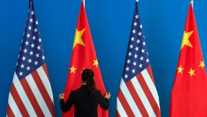 A woman adjusts a Chinese national flag next to US national flags 