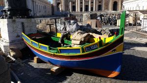 A colorfully-painted boat sits on top of a rocky sidewalk