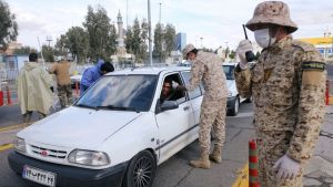 A soldier takes the temperature of someone driving a car