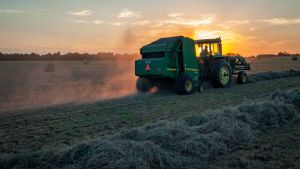 A farmer rides a tractor through a crop while harvesting