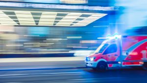 An ambulance drives past a hospital; background is blurred