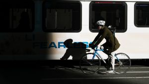 A person on a bike rides by a bus in the city.