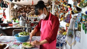 two women prepare food in mexico wearing masks 