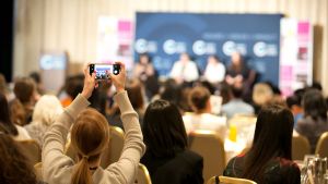A person in the audience recording a public program on their mobile phone