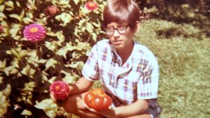 A boy in his garden holds tomatoes