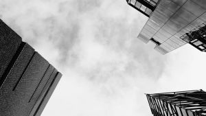 A black and white photo of the view from the ground below three skyscrapers