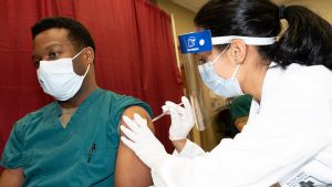 A doctor gives a person in a surgical mask a vaccine shot