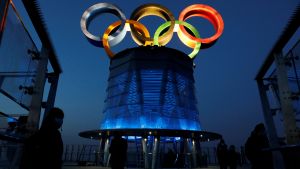 People are seen near the lit-up Olympic rings at top of the Olympic Tower, a year ahead of the opening of the 2022 Winter Olympic Games, in Beijing, China