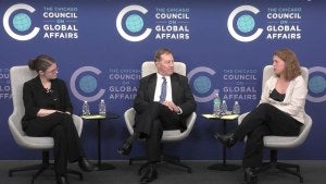 Three people sit on-stage during the live stream of a program.