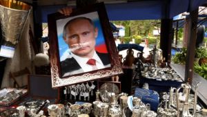 A person holds a framed photo of Vladimir Putin