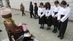 South Korean women wearing traditional dress pay their respects to a comfort-woman statue set up in front of the Japanese consulate in Busan, South Korea.