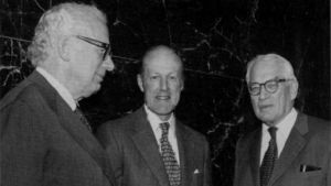 Three men in suits talk to each other