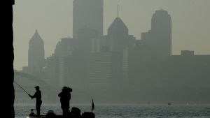 Man fishing the Ohio River in front of the Pittsburgh skyline.