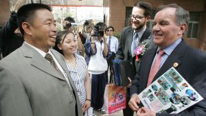 Two men laughing and one holds a newspaper