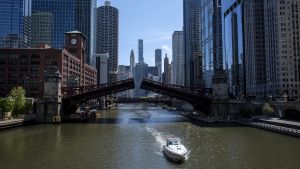 Boat headed east on the Chicago river with skyscrapers behind.