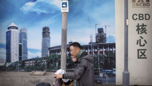 A man walking on a sidewalk in China talks on the phone