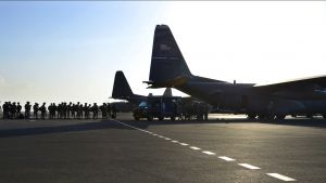 Silhouette of soldiers lining up to board a plane.