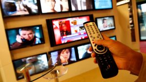 A remote control in front of a series of screens.