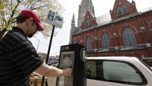 A man uses a parking meter kiosk across the street from a church