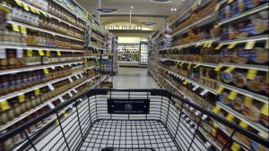 View down a grocery aisle from the front of an empty grocery cart.