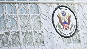 A wrought iron fence painted white with a US Embassy sign. 