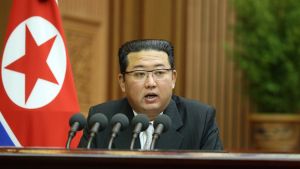 Kim Jong Un speaks at a podium in front of a North Korean flag