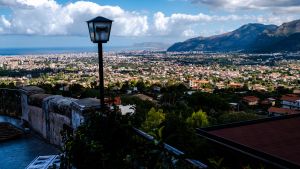 A view of Palermo from a balcony with a lamp post with blue sky and clouds.