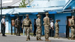 US army personnel stand in front of blue building