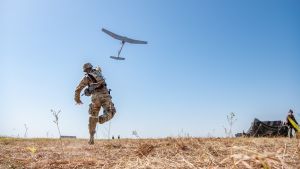 A fire control specialist with the US Army throws a RQ-11 Raven System into the blue sky during training exercise. 