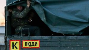 A suspected Russian soldier hides under a tarp