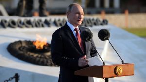 Vladimir Putin at a podium outdoors.