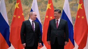 Presidents Xi Jinping and Putin standing in front of flags