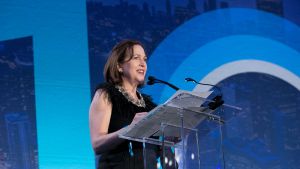 A woman speaks into a microphone behind a podium