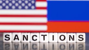 "Sanctions" on board game letters in front of Russian and American flag 