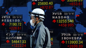 A person wearing a surgical mask walks past a digital map