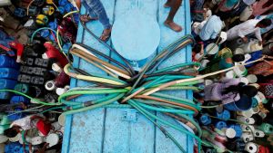 Residents fill their containers with drinking water from a blue municipal tanker with many hoses in New Delhi, India