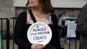 A woman holds a sign saying "Hunger is a political choice" at a World Hunger Day protest in London on May 28, 2022.