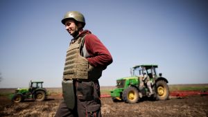 Ukrainian farmer, wearing body armour and helmet, works at the topsoil in a field, amid Russia's invasion of Ukrain
