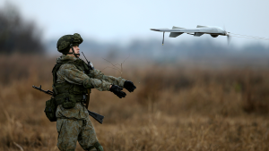 Soldier operates a remote controlled drone in a field.