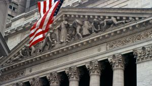 Facade of the New York Stock Exchange, with an American flag in the foreground