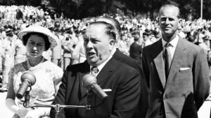 black and white photo of mayor daley making speech at a podium next to queen elizabeth II.