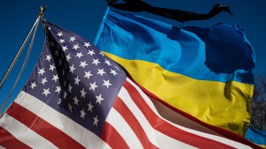 US and Ukraine flags before a blue sky.