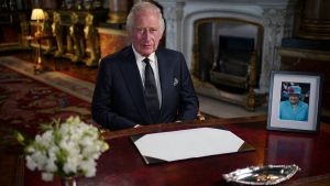King Charles III sits at a table, facing the camera