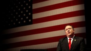 Mike Pompeo stands in front of a large American flag