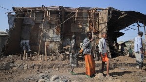 Residents and militias stand next to houses destroyed by an airstrike