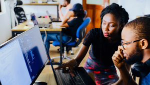 A man and a woman looking and pointing at a computer.