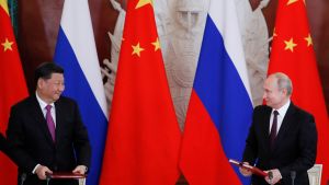 Presidents Xi and Putin look at each other while standing at separate podiums